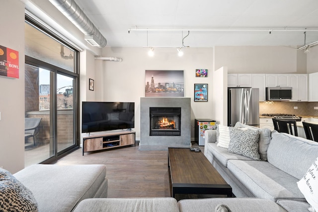 1301 W Madison St Unit 207, Chicago, IL 60607 - living area featuring rail lighting, a warm lit fireplace, light wood-style floors, and a towering ceiling