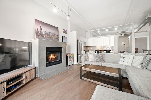 1301 W Madison St Unit 207, Chicago, IL 60607 - living room with track lighting, light wood-style floors, a lit fireplace, and a towering ceiling