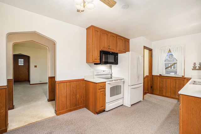 17958 Escanaba Ave, Lansing, IL 60438 - kitchen featuring white appliances, light colored carpet, a wainscoted wall, wood walls, and brown cabinetry