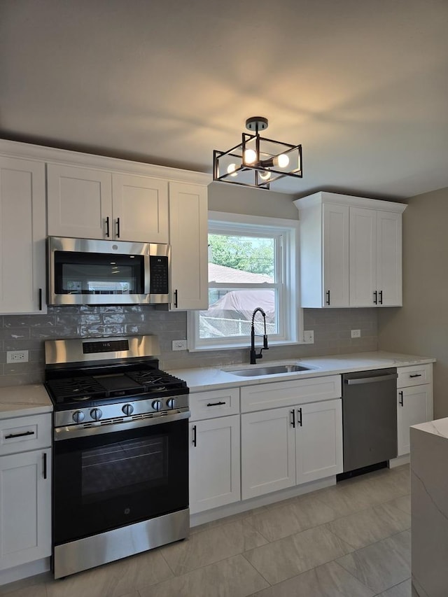 540 47th Ave, Bellwood, IL 60104 - kitchen with appliances with stainless steel finishes, light countertops, white cabinets, tasteful backsplash, and a chandelier