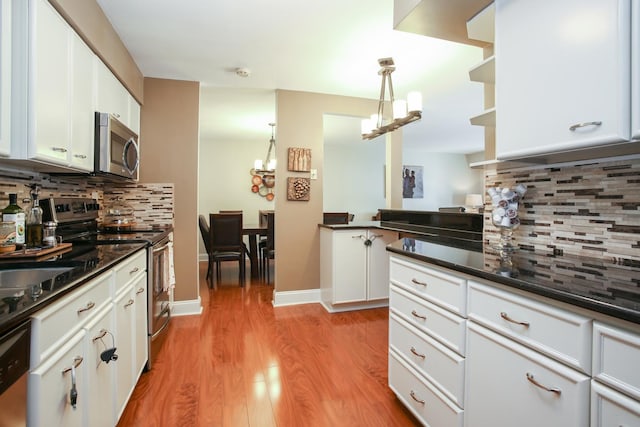 1415 E Central Rd Unit 219C, Arlington Heights, IL 60005 - kitchen with appliances with stainless steel finishes, a chandelier, backsplash, dark countertops, and light wood-style floors