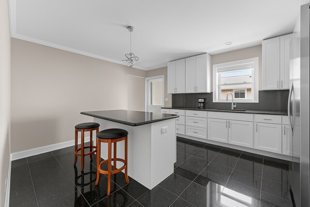 5008 Culver St, Skokie, IL 60077 - kitchen featuring dark countertops, white cabinetry, a kitchen island, a kitchen bar, and stainless steel refrigerator