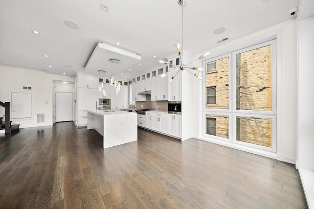 702 W Wellington Ave Unit 2N, Chicago, IL 60657 - kitchen with stainless steel appliances, a chandelier, glass insert cabinets, light countertops, and pendant lighting