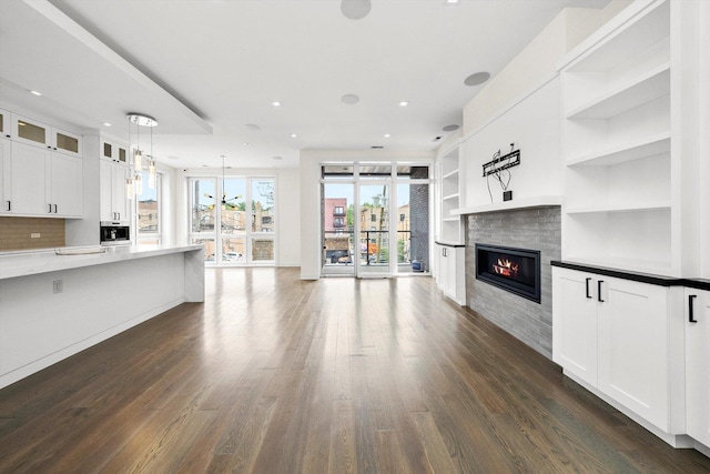 702 W Wellington Ave Unit 2N, Chicago, IL 60657 - kitchen with dark wood-type flooring, a glass covered fireplace, white cabinetry, glass insert cabinets, and open floor plan