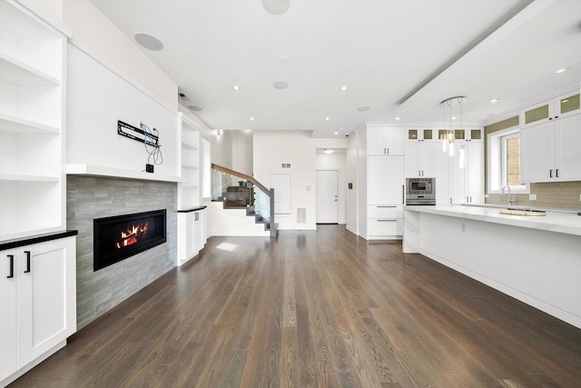 702 W Wellington Ave Unit 2N, Chicago, IL 60657 - unfurnished living room featuring a tile fireplace, dark wood-style floors, stairs, built in features, and recessed lighting
