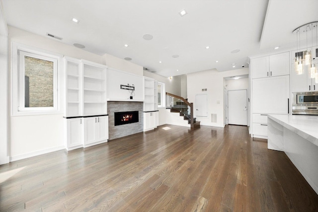702 W Wellington Ave Unit 2N, Chicago, IL 60657 - unfurnished living room featuring wood finished floors, a warm lit fireplace, stairway, and recessed lighting