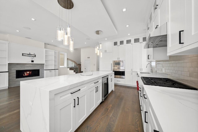 702 W Wellington Ave Unit 2N, Chicago, IL 60657 - kitchen featuring wine cooler, built in microwave, oven, under cabinet range hood, and a center island