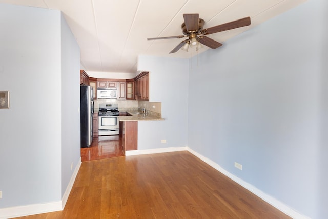 1633 River St Unit 2B, Des Plaines, IL 60016 - kitchen with white microwave, gas range, freestanding refrigerator, a ceiling fan, and wood finished floors