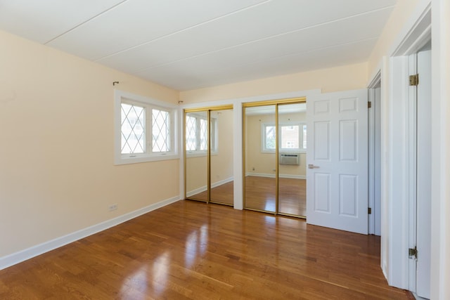 1633 River St Unit 2B, Des Plaines, IL 60016 - unfurnished bedroom featuring two closets, wood finished floors, and an AC wall unit