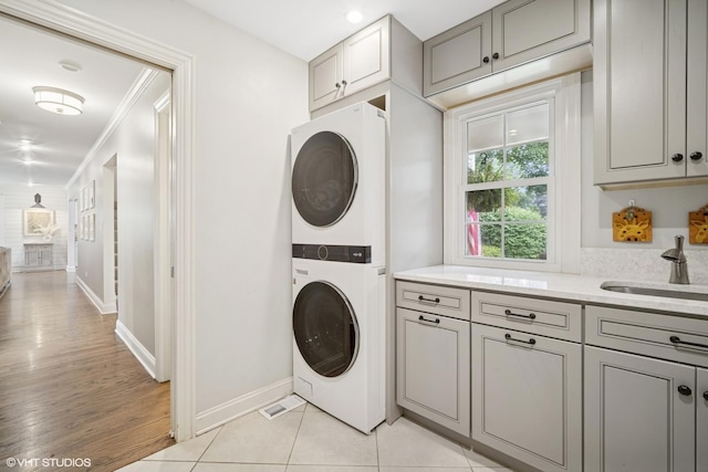 2113 Berwick St, Inverness, IL 60067 - laundry room with stacked washing machine and dryer, cabinet space, crown molding, and light wood-style floors
