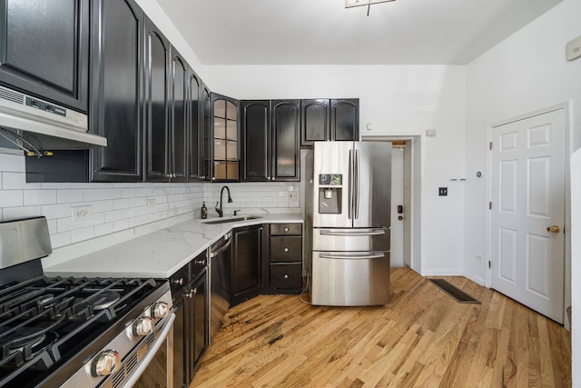 3722 S Wabash Ave, Chicago, IL 60653 - kitchen featuring appliances with stainless steel finishes, backsplash, under cabinet range hood, light wood-style flooring, and light stone counters
