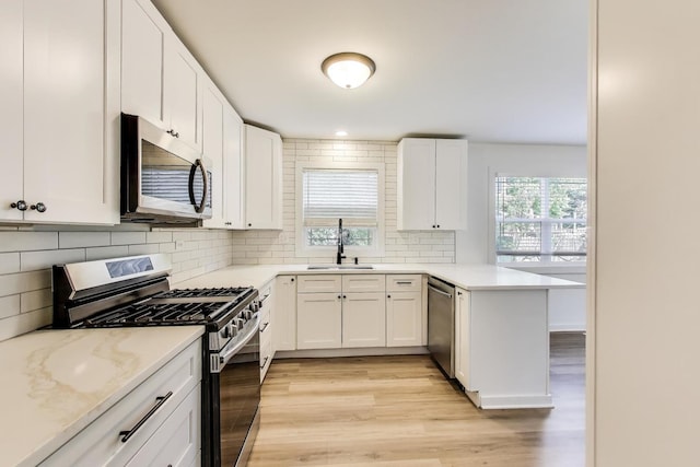 1329 Neskola Ct, Naperville, IL 60564 - kitchen with appliances with stainless steel finishes, light wood-style floors, tasteful backsplash, white cabinets, and a peninsula