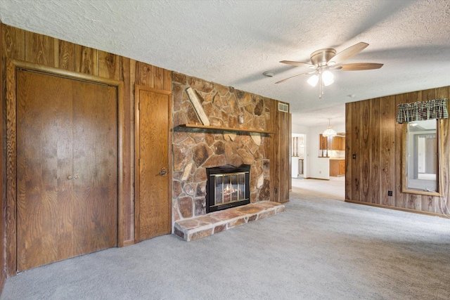 1619 Arnold Ave, Rockford, IL 61108 - unfurnished living room with wood walls, carpet floors, ceiling fan, a textured ceiling, and a stone fireplace