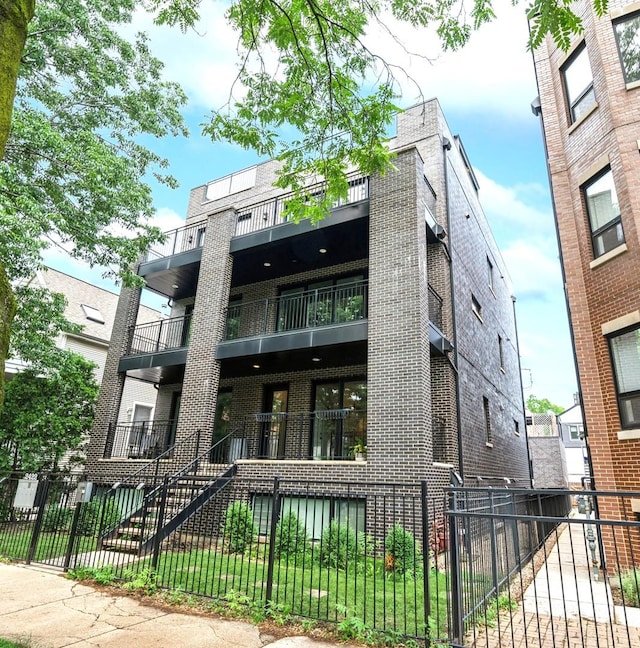 2422 W Lyndale St Unit 1E, Chicago, IL 60647 - view of front of house featuring a balcony, a fenced front yard, brick siding, and a gate