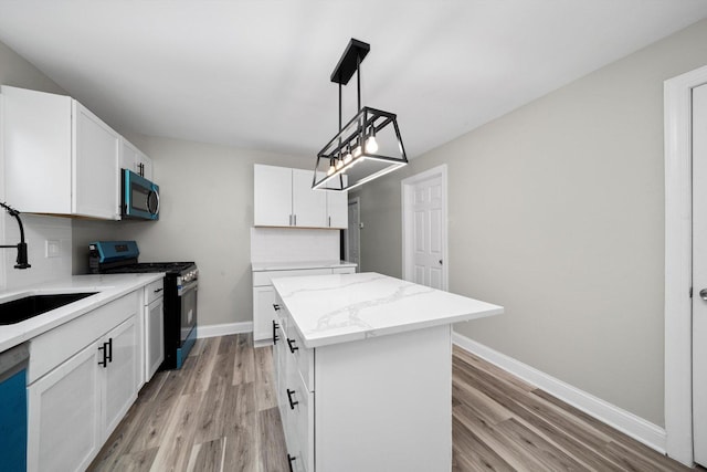 10823 S Ewing Ave, Chicago, IL 60617 - kitchen featuring stainless steel microwave, range with gas cooktop, a center island, and light wood-style flooring