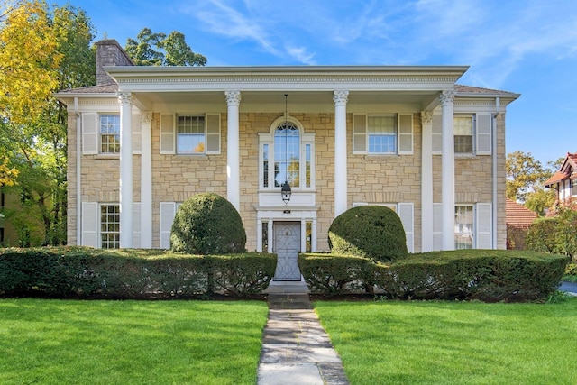 424 Sheridan Rd, Kenilworth, IL 60043 - greek revival house with stone siding, a front yard, and a chimney