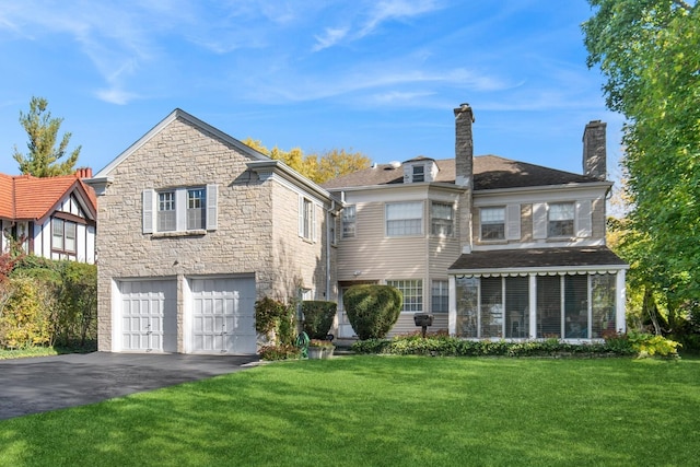 424 Sheridan Rd, Kenilworth, IL 60043 - back of property with asphalt driveway, a garage, stone siding, a lawn, and a chimney