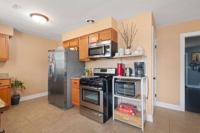 251 W 10th St, Chicago Heights, IL 60411 - kitchen featuring appliances with stainless steel finishes, light tile patterned flooring, brown cabinets, and light stone counters
