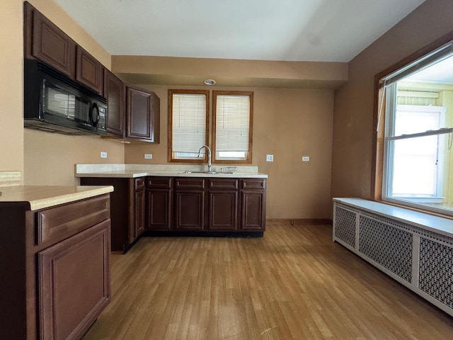 1304 S 50th Ave, Cicero, IL 60804 - kitchen featuring radiator, black microwave, light wood finished floors, and light countertops