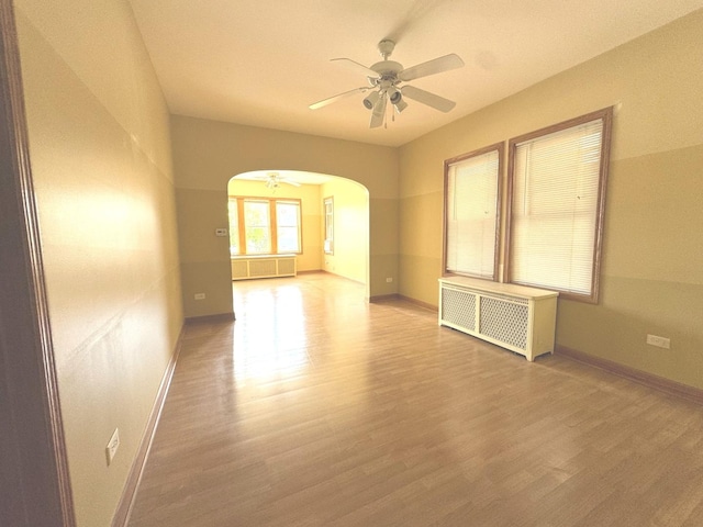 1304 S 50th Ave, Cicero, IL 60804 - empty room featuring radiator heating unit, ceiling fan, arched walkways, and wood finished floors