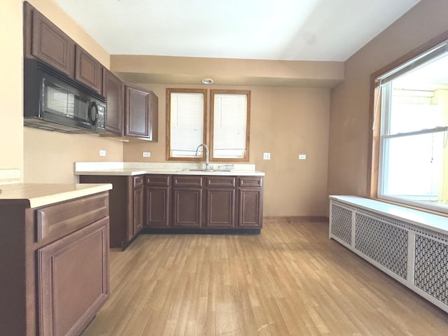 1304 S 50th Ave, Cicero, IL 60804 - kitchen with radiator, black microwave, light wood-style flooring, light countertops, and plenty of natural light
