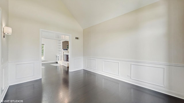 392 Spruce Rd, Wood Dale, IL 60191 - spare room with a decorative wall, wainscoting, a fireplace with raised hearth, dark wood-style floors, and high vaulted ceiling