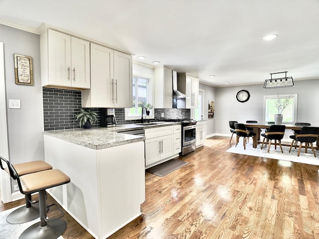 120 Walter Ct, Bloomingdale, IL 60108 - kitchen with stainless steel range with gas stovetop, wall chimney range hood, plenty of natural light, decorative backsplash, and ornamental molding