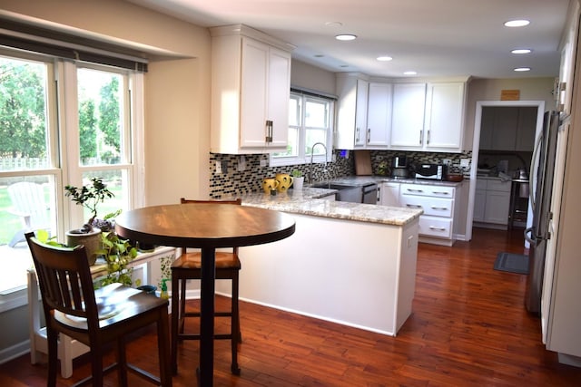 46 Copperwood Dr, Buffalo Grove, IL 60089 - kitchen featuring a peninsula, white cabinetry, backsplash, freestanding refrigerator, and light stone countertops