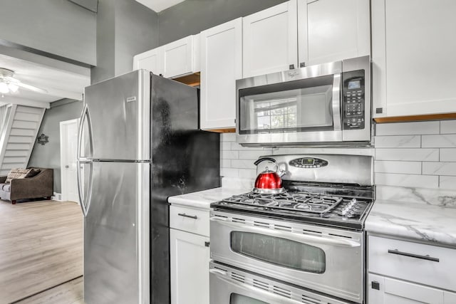 41607 N Lotus Ave, Antioch, IL 60002 - kitchen featuring stainless steel appliances, white cabinets, light stone counters, and decorative backsplash