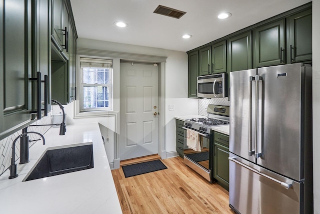 1654 W Berwyn Ave Unit 2W, Chicago, IL 60640 - kitchen featuring appliances with stainless steel finishes, green cabinets, light countertops, decorative backsplash, and recessed lighting