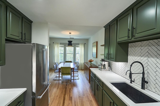 1654 W Berwyn Ave Unit 2W, Chicago, IL 60640 - kitchen featuring green cabinetry, freestanding refrigerator, light wood-style flooring, decorative backsplash, and light countertops