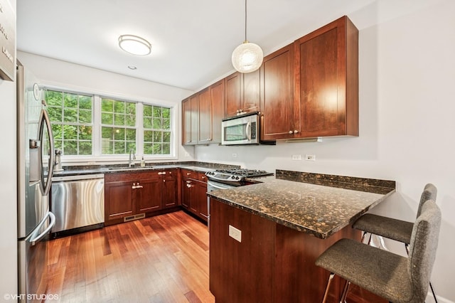 1657 Church St, Evanston, IL 60201 - kitchen with stainless steel appliances, a peninsula, hardwood / wood-style floors, a kitchen bar, and dark stone counters