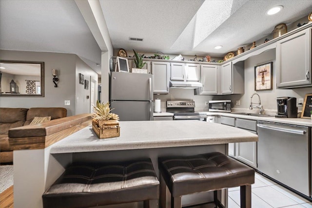 903 N Linden St Unit 131, Normal, IL 61761 - kitchen with stainless steel appliances, under cabinet range hood, light countertops, a textured ceiling, and a kitchen bar