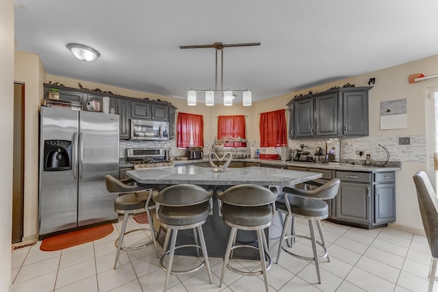 22401 Helen Dr, Sauk Village, IL 60411 - kitchen with appliances with stainless steel finishes, decorative backsplash, light tile patterned flooring, a breakfast bar, and a center island