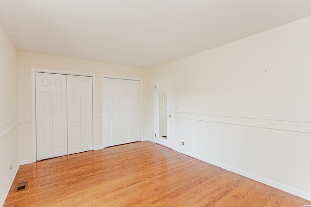 590 Green Bay Rd, Glencoe, IL 60022 - unfurnished bedroom featuring multiple closets and light wood-type flooring