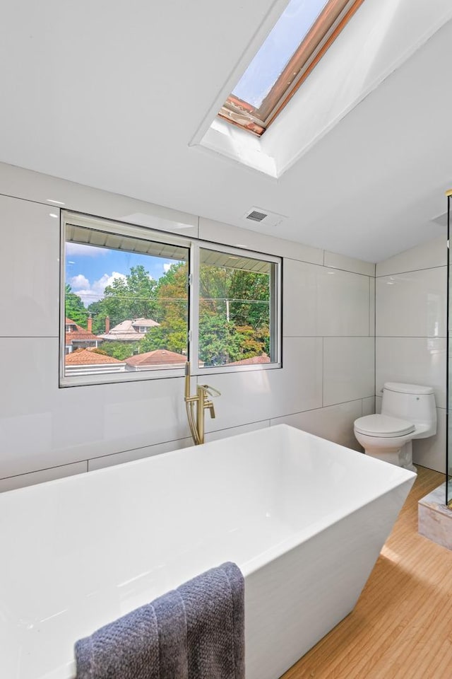 605 Home Ave, Oak Park, IL 60304 - bathroom with a freestanding bath, wood finished floors, a skylight, and tile walls