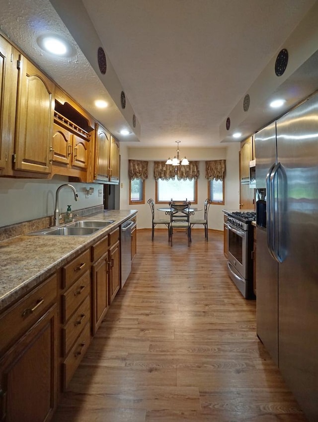 6924 Cody Ln, Rockford, IL 61107 - kitchen featuring stainless steel appliances, wood finished floors, a chandelier, decorative light fixtures, and brown cabinets
