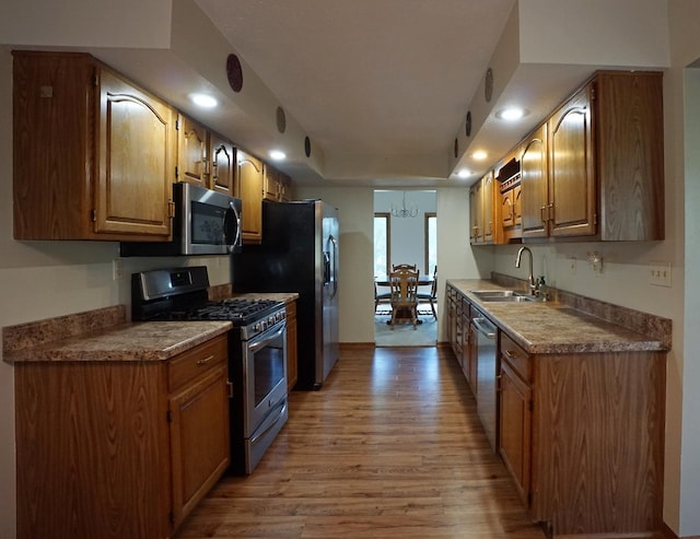 6924 Cody Ln, Rockford, IL 61107 - kitchen with stainless steel appliances, light wood-type flooring, recessed lighting, a tray ceiling, and brown cabinetry