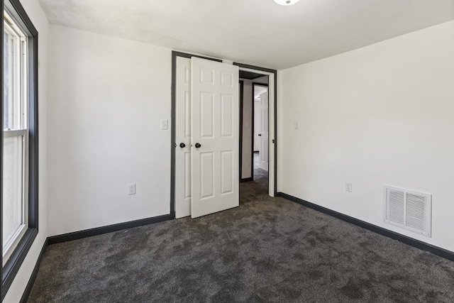 1213 W Fourth St, Dixon, IL 61021 - unfurnished bedroom featuring dark carpet, a closet, and multiple windows