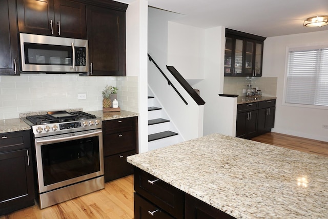 4452 N Newland Ave, Harwood Heights, IL 60706 - kitchen featuring appliances with stainless steel finishes, light wood-style floors, decorative backsplash, and light stone countertops