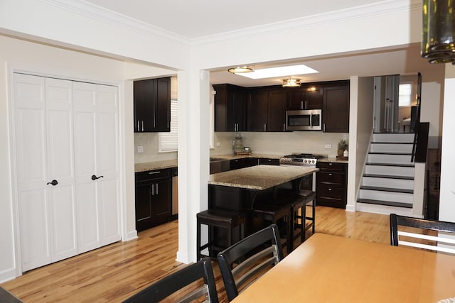 4452 N Newland Ave, Harwood Heights, IL 60706 - kitchen featuring stainless steel appliances, light wood-style floors, a breakfast bar, tasteful backsplash, and ornamental molding