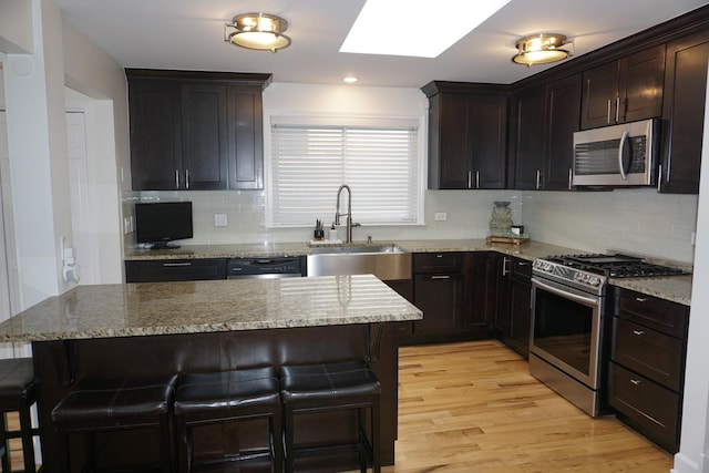 4452 N Newland Ave, Harwood Heights, IL 60706 - kitchen featuring stainless steel appliances, a skylight, a kitchen breakfast bar, light wood finished floors, and decorative backsplash