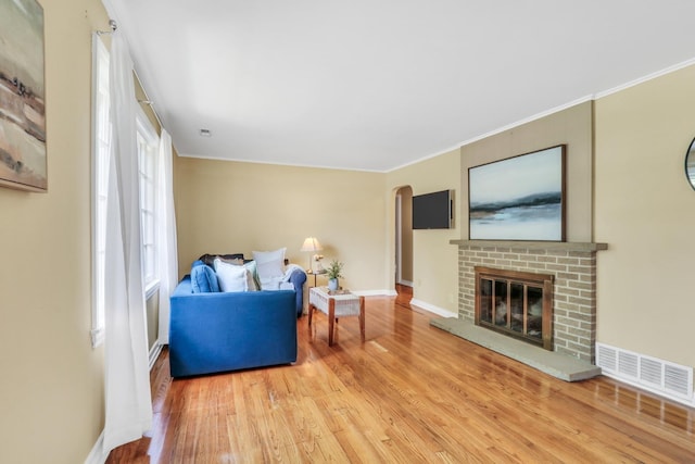137 School St, Grayslake, IL 60030 - living room featuring light wood-type flooring, a fireplace, arched walkways, and crown molding