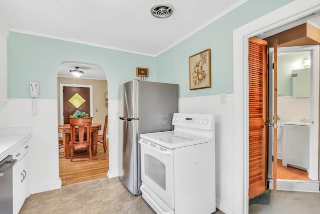 137 School St, Grayslake, IL 60030 - kitchen featuring stainless steel appliances, arched walkways, ornamental molding, a wainscoted wall, and light countertops