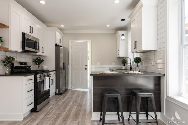 7945 S Avalon Ave, Chicago, IL 60619 - kitchen featuring appliances with stainless steel finishes, dark countertops, white cabinetry, a peninsula, and a kitchen bar