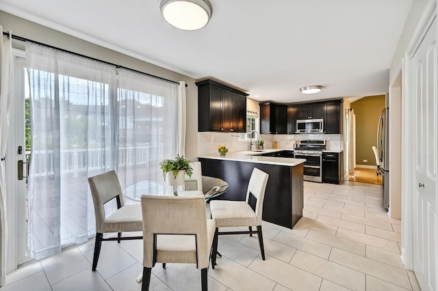 1501 Pine View Ct, Darien, IL 60561 - kitchen featuring appliances with stainless steel finishes, light countertops, a peninsula, backsplash, and dark cabinets