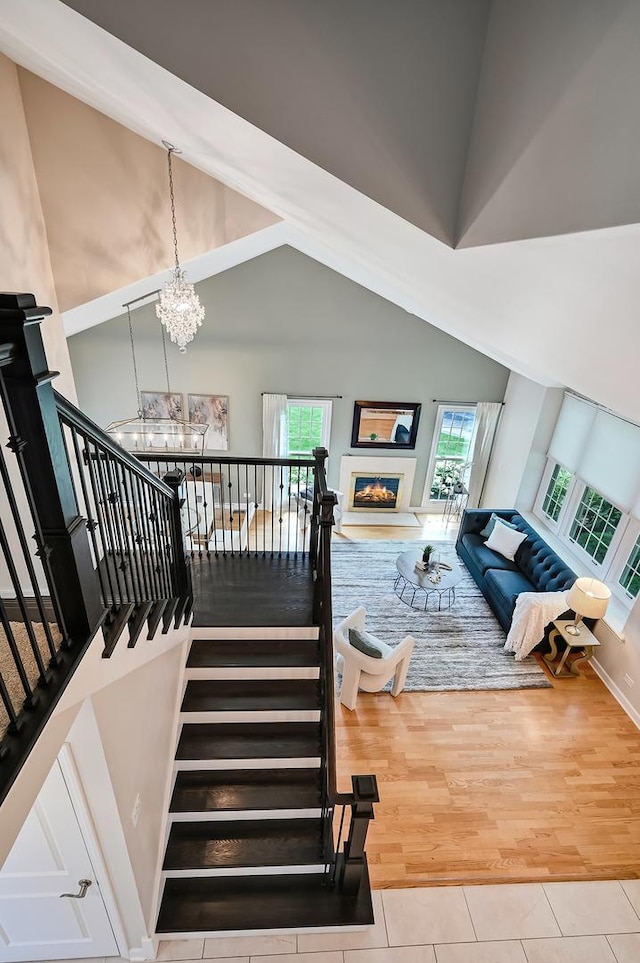 1501 Pine View Ct, Darien, IL 60561 - stairway featuring a chandelier, tile patterned floors, high vaulted ceiling, and a glass covered fireplace