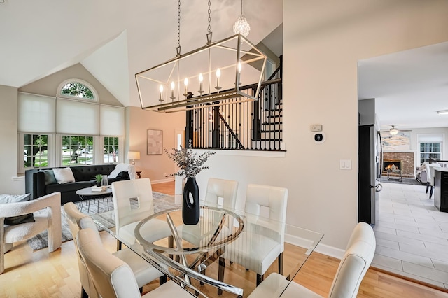 1501 Pine View Ct, Darien, IL 60561 - dining room featuring light wood-style flooring, a chandelier, a stone fireplace, high vaulted ceiling, and a ceiling fan