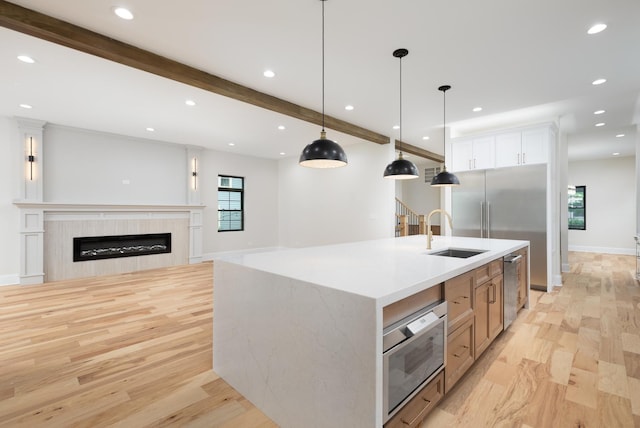 223 Center St, Naperville, IL 60540 - kitchen with appliances with stainless steel finishes, light wood-style flooring, decorative light fixtures, a glass covered fireplace, and beam ceiling