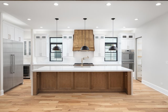 223 Center St, Naperville, IL 60540 - kitchen with appliances with stainless steel finishes, custom exhaust hood, wine cooler, light wood finished floors, and light countertops